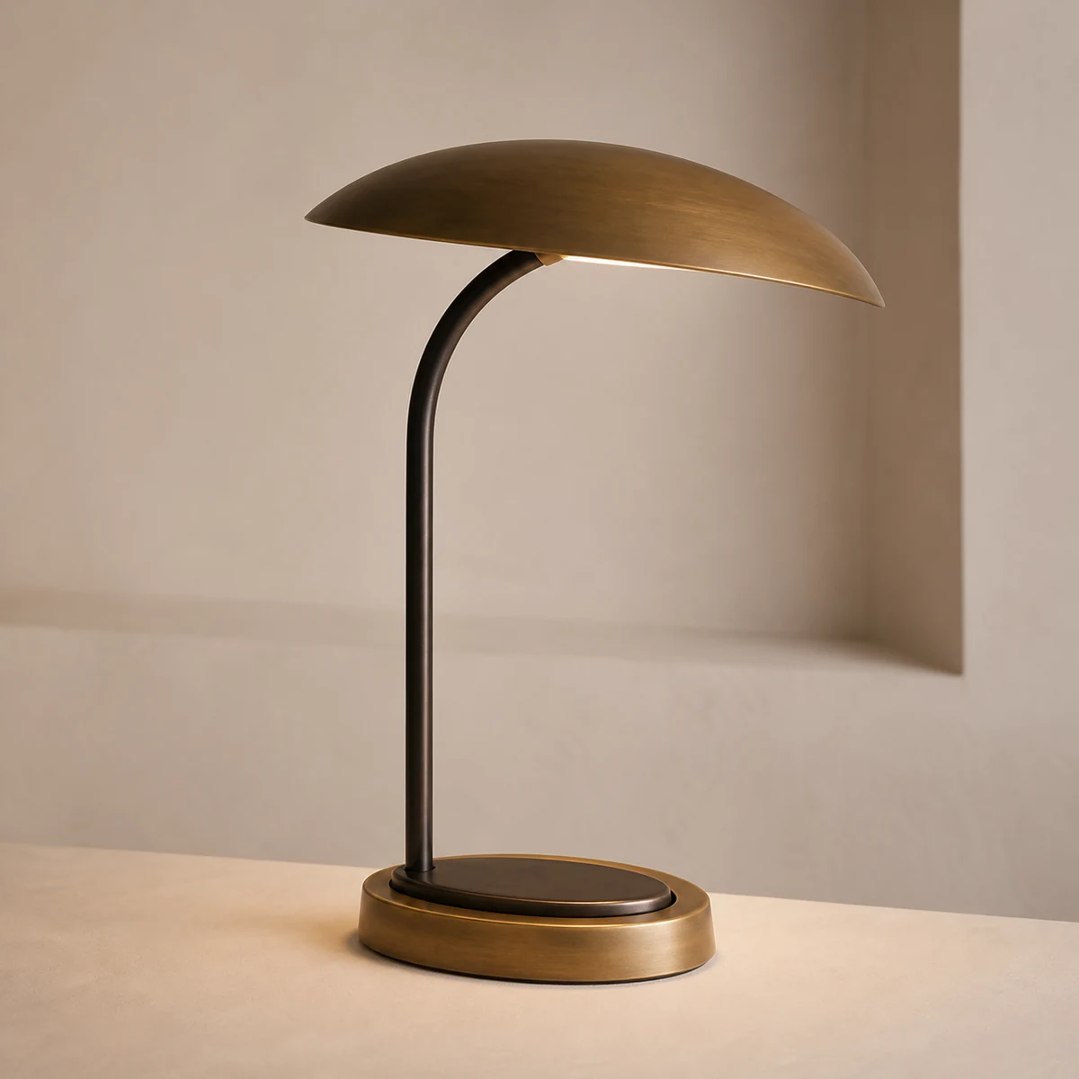 Arc Canopy table lamp concept with a dark curved stem, oval brass shade, and compact round base